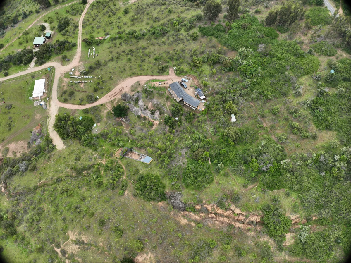 Fotografía aérea real de caminos, construcciones y vegetación del predio